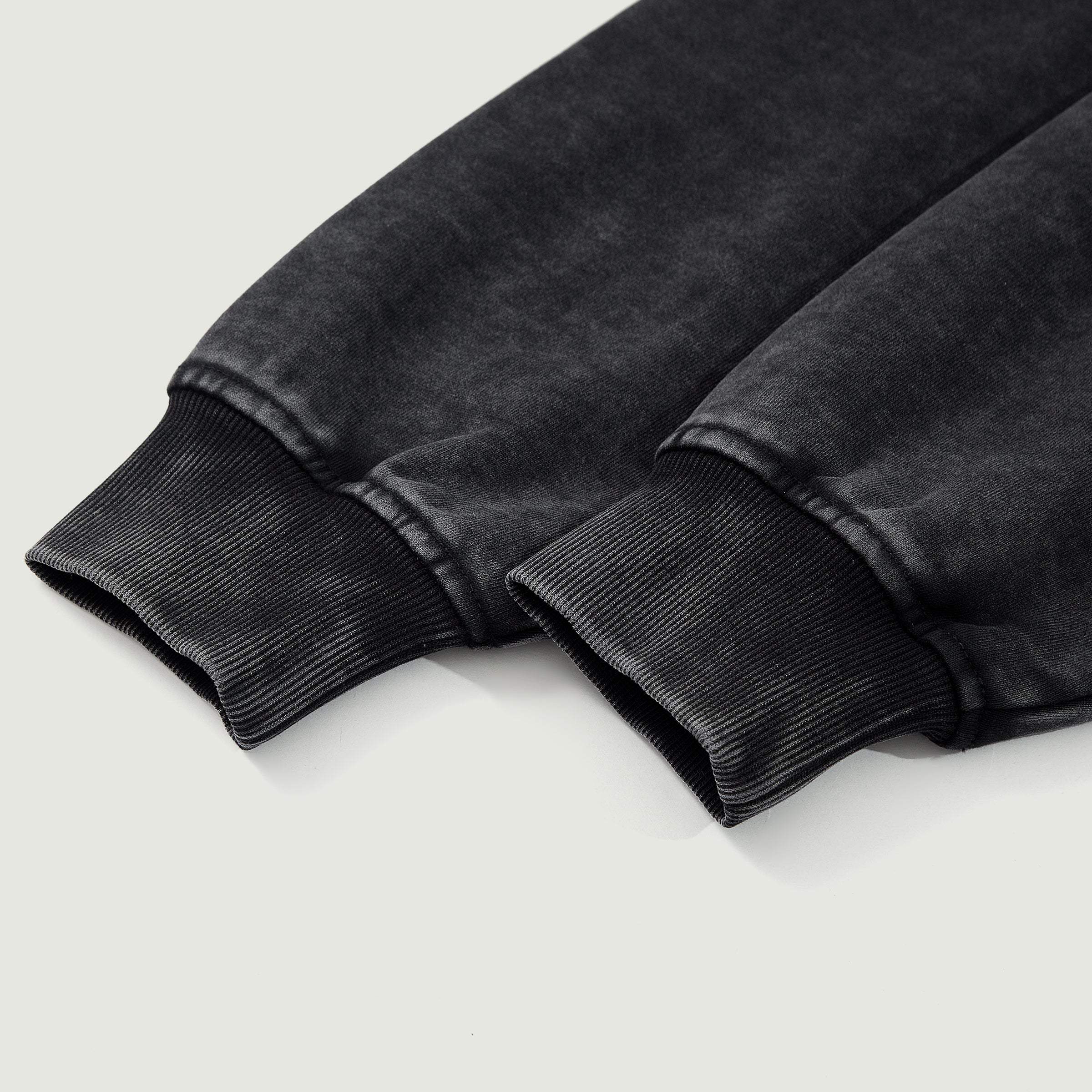 Close-up of black washed streetwear sweatshirt cuffs on a light background