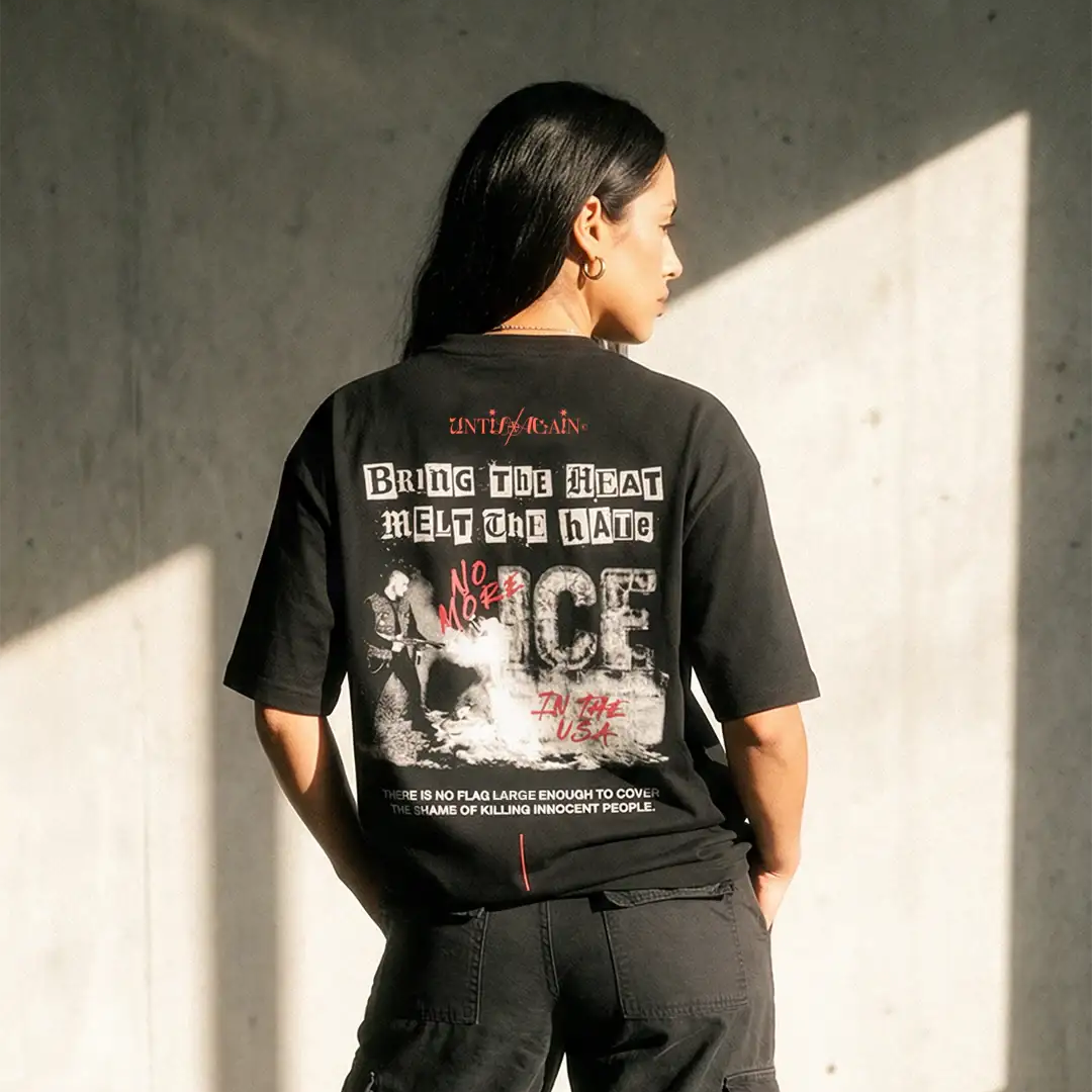 Woman wearing black streetwear graphic tee with bold protest text and cargo pants, sunlight background