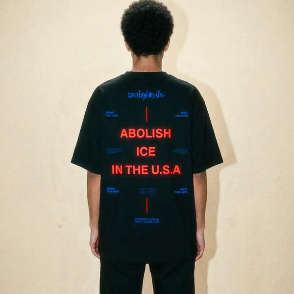 Back view of a person wearing a black streetwear t-shirt with bold red protest text.